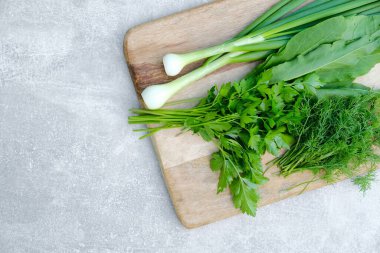 Taze çiğ sebzeli ahşap kesme tahtası: yeşil soğan, maydanoz, dereotu, doru. Taze ve sağlıklı organik gıdalar..