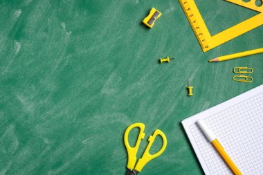 Okul konseptine geri dönelim. Düz sarı okul kağıtları ve yeşil karatahtaya kağıt defter. Üst görünüm, genel görünüm.