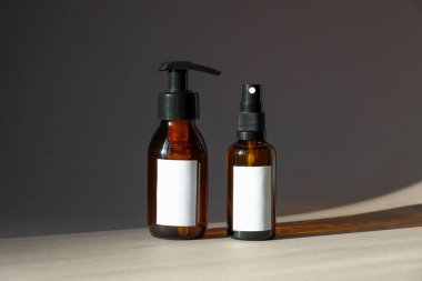 Kehribar cam kozmetik şişeleri. Doğal el kremiyle pompa şişesi ve vücut losyonuyla sprey şişesi. Kozmetik ürün paketleme tasarımı