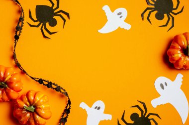 Cadılar Bayramı parti dekorasyonları, hayaletler, örümcekler, turuncu arka planda balkabakları. Düz yerde, üst tarafta. Cadılar Bayramı kartı modeli.