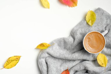 Düz sonbahar kompozisyonu. Bir fincan kahve, örgü gri kazak, beyaz arka planda kurumuş yapraklar. Sonbahar, sonbahar konsepti.