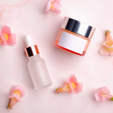 Kozmetik krem kavanozu ve pembe arka planda yapraklı losyon şişesi. Cilt bakımı güzellik ürünleri paketleme tasarımı.