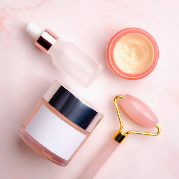 ピンクの背景で顔の治療のための化粧品ボトルやアクセサリーを表示します 美容製品パッケージデザイン — ストック写真