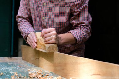 Marangoz dükkanında ahşap planörle çalışan kadın marangoz. DIY, ahşap konsepti.
