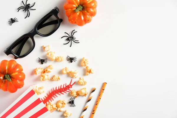 Halloween party decorations on white desk. Flat lay, top view pumpkins, glasses, popcorn, spiders. Halloween background.