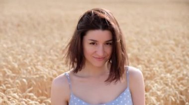 Buğday tarlasında güzel beyaz bir kadın, yakın plan portresi. Olumlu kız gülümsüyor, yazın tadını çıkarıyor..