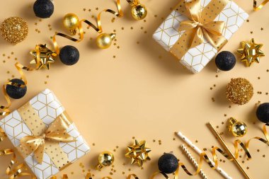 Noel veya Yeni Yıl kompozisyonu. Altın ve siyah renklerde Noel süsleri ve altın arka planda hediye kutuları ve metin için fotokopi alanı. Düz yatış, üst görünüm.
