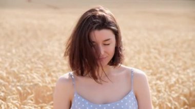 Kameraya bakan kısa saçlı neşeli genç bir kadının yakın plan portresi. Beyaz kız gün batımında buğday tarlasında poz veriyor. Doğal güzellik insanları..