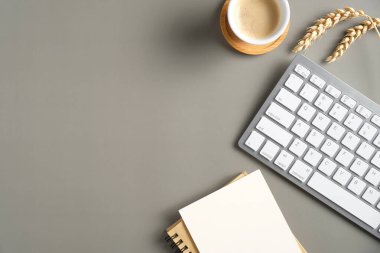 Üst manzara, düz klavye, bir fincan kahve, kağıt defter, ofis masasında buğday. Sonbahar stili çalışma alanı.