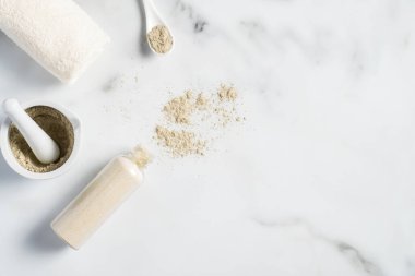 Ayurvedic yüz maskesi. Gram unu / besan kullanılıyor. Kâseye, havluya ve mermer masaya konmuş haldi ubtan. Doğal SPA kozmetikleri.