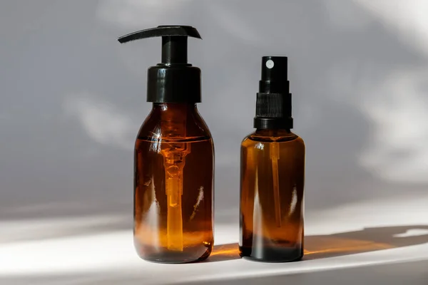 Set of amber glass bottles without labels on white background. Pump dispenser bottle with shampoo and spray perfume. Cosmetic packaging design.