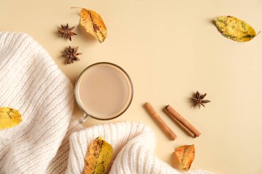 Sonbahar düz kompozisyonu beyaz örgü eşarp, kahve fincanı, tarçın çubukları, bej arka planda düşmüş yapraklar. Rahat ev masası, hygge tarzı..