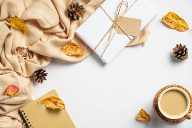 Sonbahar düz kompozisyonu bej ekose, hediye kutusu, kahve fincanı, çam kozalakları, beyaz arka planda düşen yapraklar. Sonbahar, sonbahar konsepti.