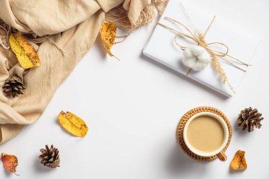 Sonbahar kompozisyonu. Düz yatak, el yapımı hediye kutusu, kahve fincanı, bej eşarp, kuru yapraklar, çam kozalakları. Sonbahar tatili, sonbahar konsepti.