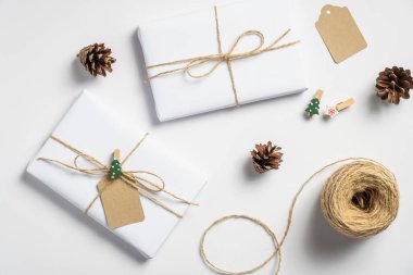 Noel arkaplanı hediye kutuları, ip, beyaz üzerine çam kozalakları. Tatil hazırlığı. Çevre dostu Noel hediyeleri, sıfır atık konsepti.
