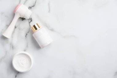 Yüz bakımı kozmetik ürünleri mermer masada. Düz yatak, üst görünüm losyon şişesi, nemlendirici krem, masaj fırçası. SPA banyo güzellik ürünleri seti. Yaşlanma, kaldırma, yüz bakımı.