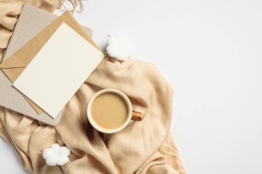 Sıcak ev masası, bej eşarp, kahve fincanı, boş kağıt not defteri, beyaz arka planda pamuk. Sonbahar ya da kış tatili konsepti. Hygge tarzı, düz yatış, üst görünüm.