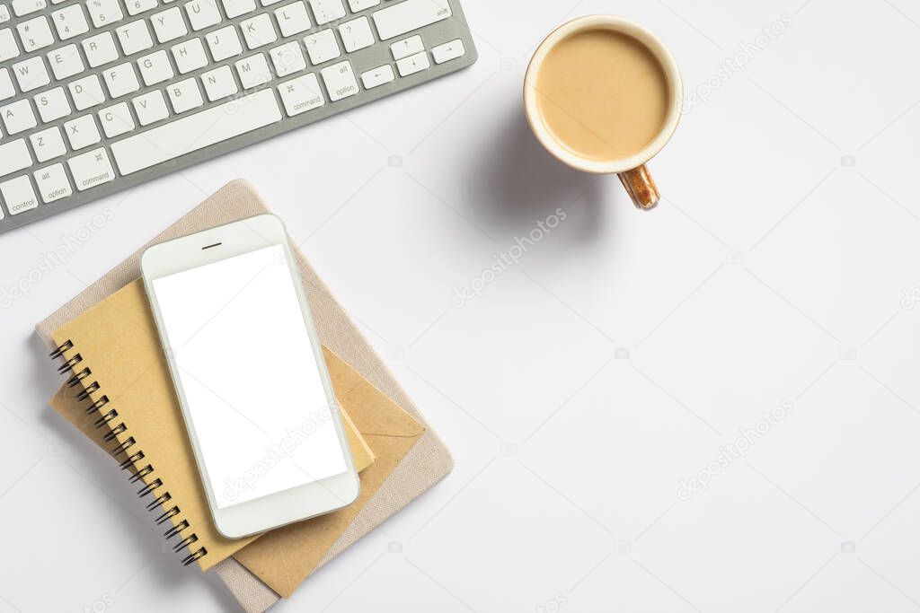 Modern office desk table with pc keyboard, coffee cup, paper notebook, smartphone mockup with blank screen on white background. Flat lay, top view. Minimal style workspace.