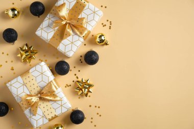 Altın ve siyah süslemeli Noel kartı şablonu. Düz yatıyordu, üst düzey Xmas hediyeleri, takılar, süsler, pastel sarısı arka planda konfeti. Noel afişi modeli.