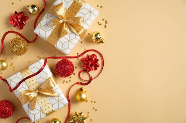 Noel kompozisyonu. Düz Noel hediyeleri, kırmızı ve altın toplar süslemeler, süslemeler, pastel sarı masanın üzerinde konfeti. Xmas ve Yılbaşı tatili geçmişi.