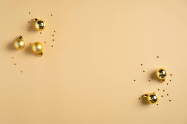 Noel kartı maketi. Noel düz kompozisyonu, altın toplar süslemeleri ve pastel sarısı arka planda konfetileri vardı. Kopyalama alanı olan üst görünüm.