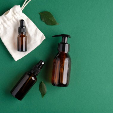 Yeşil yapraklı sıfır atık organik SPA kozmetik ürünleri. Yeşil arka planda kehribar cam şişeler. Doğal cilt bakım ürünleri paketleme tasarımı.