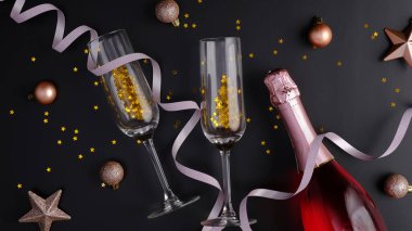 Noel kompozisyonu. Gül şarabı şişesi, bardaklar, Xmas topları, siyah arka planda süslemeler. Noel kutlaması kavramı. Düz yatış, üst görünüm.