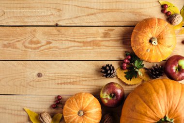 Balkabaklarından, kurumuş yapraklardan, elmalardan, fındıklardan, kozalaklardan oluşan sonbahar çerçevesi ahşap masada. Şükran Günü ya da Sonbahar Hasat konsepti. Düz konum, üst görünüm, kopyalama alanı