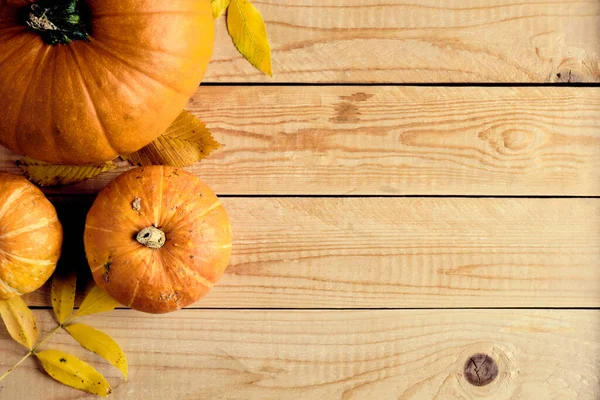 Autumn frame made of pumpkins and fallen leaves on wooden table. Halloween, Thanksgiving, Autumn fall concept. Flat lay composition, top view, copy space