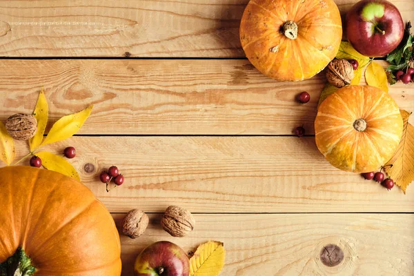 Şükran Günü konseptin kutlu olsun. Sonbahar kompozisyonu portakal kabakları, düşen yapraklar, meyveler, kırsal ahşap masada fındıklar. Düz konum, üst görünüm, kopyalama alanı. Şükran Günü geçmişi.