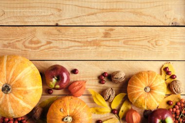 Sonbahar kompozisyonu. Kabaklardan, düşmüş yapraklardan, cevizlerden, elmalardan, ahşap masadaki kırmızı dutlardan yapılmış çerçeve kenarı. Düz konum, üst görünüm, kopyalama alanı. Şükran Günü, Sonbahar Sonbaharı, Hasat Konsepti.