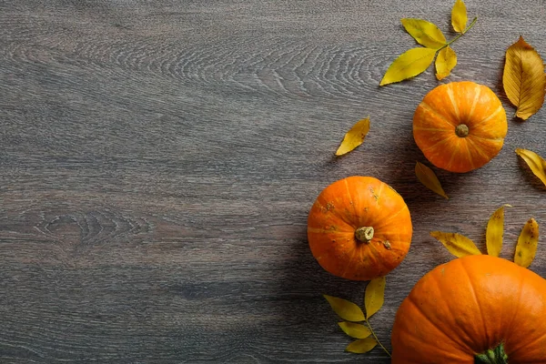 Autumn composition with ripe pumpkins and dry leaves on wooden table. Flat lay, top view, copy space. Happy Thanksgiving day concept.