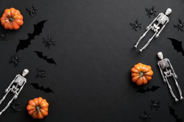 Cadılar Bayramı düz kompozisyon. İskeletler, balkabakları, örümcekler, siyah arkaplanda yarasa siluetleri. Cadılar Bayramı afişi, tebrik kartı şablonu