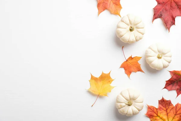 Autumn maple leaves and pumpkins on white background. Flat lay, minimal style composition. Top view.