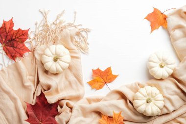 Sonbahar kompozisyonu. Küçük beyaz balkabaklarıyla kadınsı masa masası, renkli akçaağaç yaprakları ve bej eşarp. Düz yerde, üst tarafta. İskandinav, higge, konforlu ev kavramı