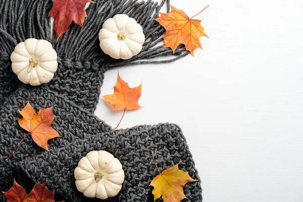 Autumn composition. Feminine desk table with knitted scarf, pumpkins, fall maple leaves on white background. Flat lay, top view. Nordic, hygge, cozy home concept