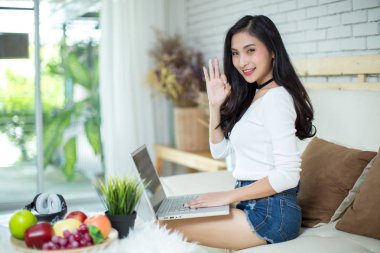 Genç ve güzel bir kadın evde dizüstü bilgisayar kullanıyor..