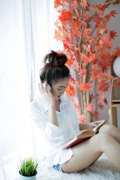 Krásná mladá žena čtení knihy u okna doma — Stock fotografie