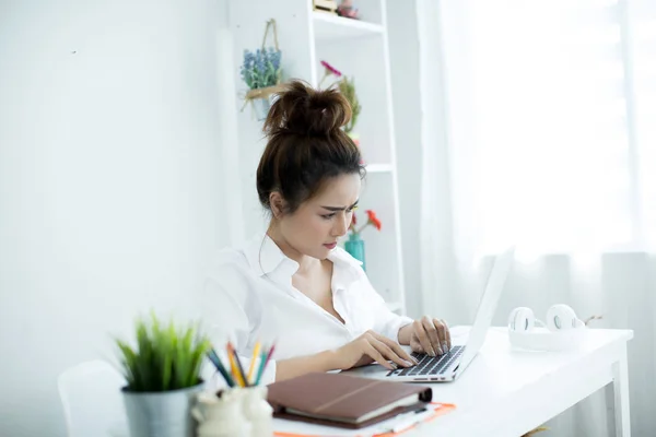 Beautiful young woman working on her laptop in her room. — ストック写真