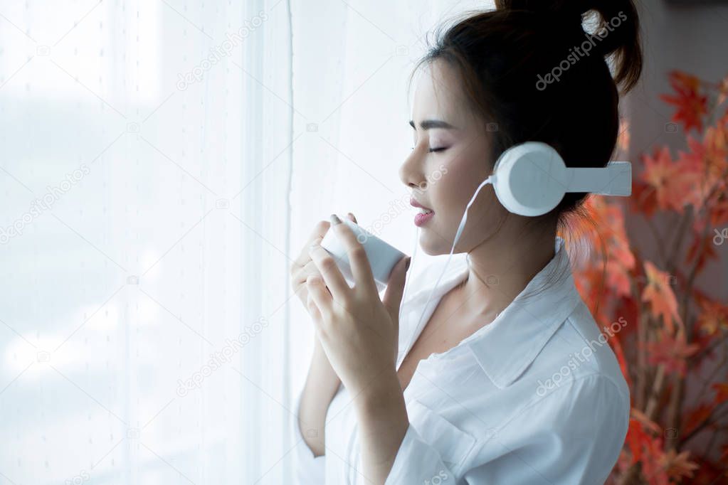 oung beautiful woman in bright outfit enjoying the music at home