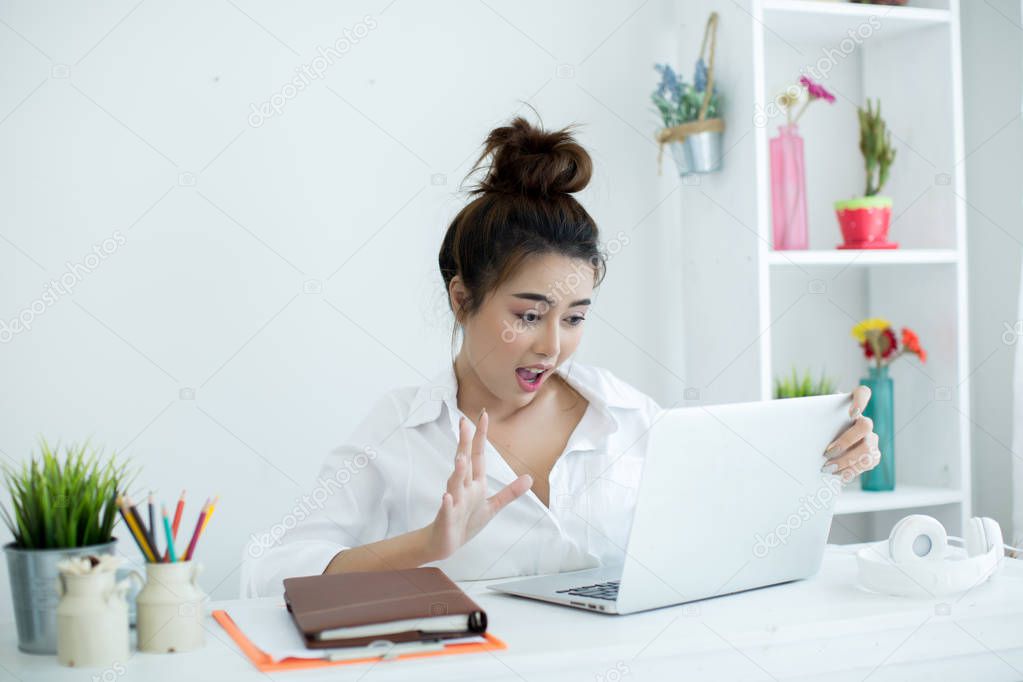 Beautiful young woman working on her laptop in her room.