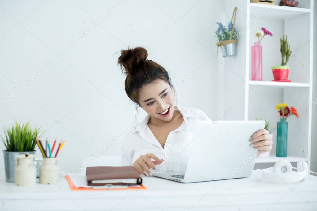 Beautiful young woman working on her laptop in her room.