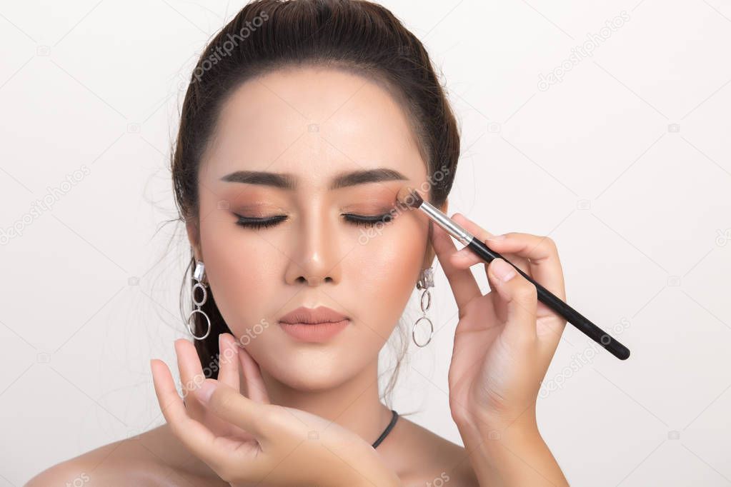 Beautiful woman face. Hand of make-up