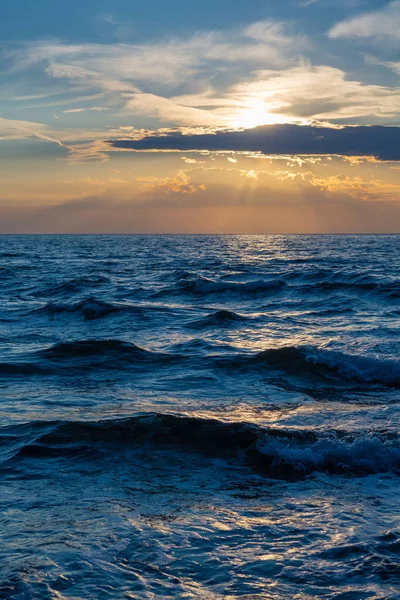 Хвилясте море і сонце ховаються за хмарами під час заходу сонця — стокове фото