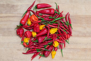 Karışık kırmızı, yeşil, turuncu ve sarı sıcak biber ahşap bir masa üzerinde