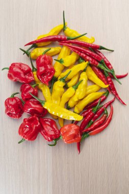 Karışık kırmızı, turuncu ve sarı sıcak biber ahşap bir masa üzerinde demet
