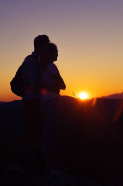 Genç çift dağların üzerinden muhteşem gün batımını izlemek