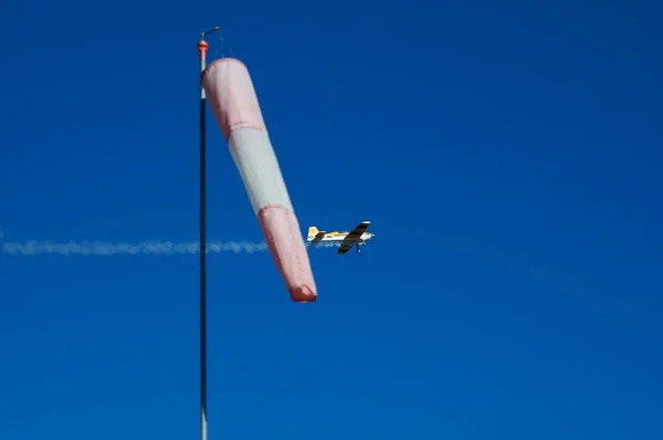 Rüzgâr tulumu ve mavi gökyüzü üzerinde arka planda akrobatik uçak — Stok fotoğraf