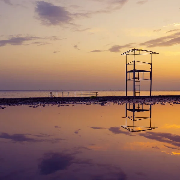 Вежа рятувальників, що відбивається у воді на красивому заході сонця — стокове фото