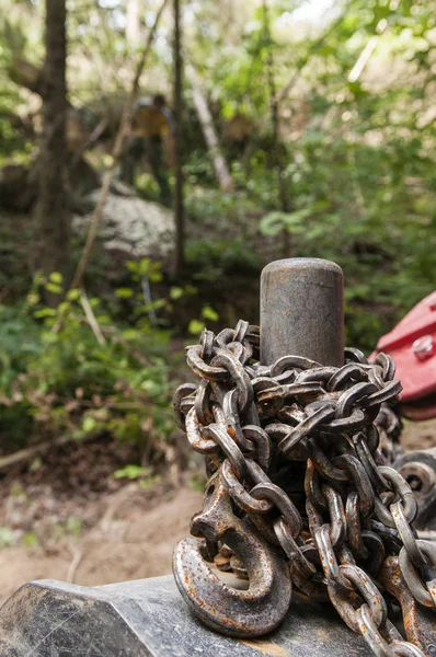 Ржавая лесозаготовительная цепь и лесной работник на заднем плане — стоковое фото